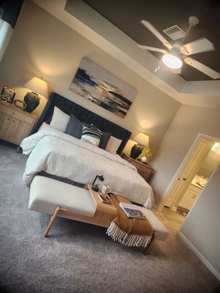 A cozy bedroom featuring a stylish bed, elegant lighting, and modern artwork, providing a serene retreat.
