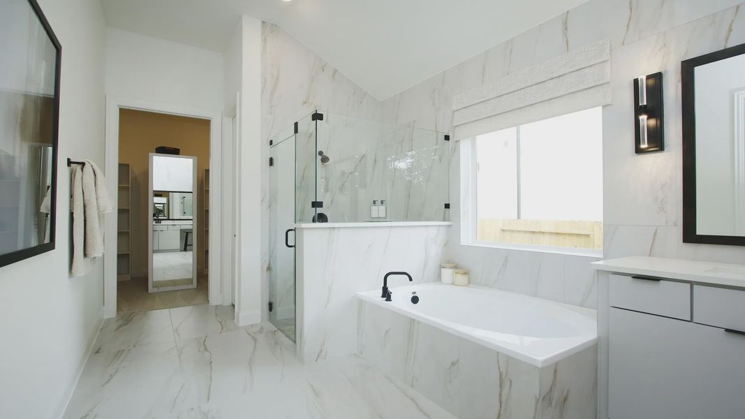 Sophisticated marble tiles grace this Woodlands Hills bathroom, boasting a sleek glass shower and sumptuous tub.