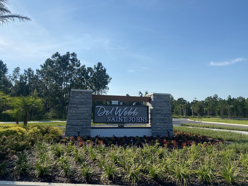 Entrance to Del Webb Saint Johns by Del Webb, showcasing lush landscaping and a welcoming stone sign in St. Johns, FL.