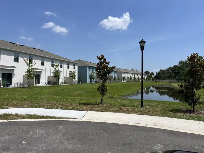 Townhomes with serene pond and green spaces in Chelsea Court by D.R. Horton (Tampa, FL).