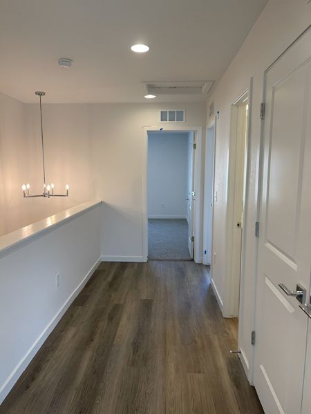 A well-lit upstairs hallway with wood flooring, modern fixtures, and a sleek, open layout.