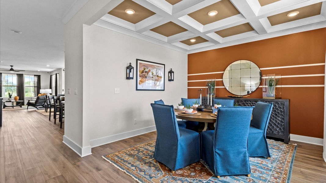 Stunning coffered ceiling dining room with brown accents and hardwood flooring at Iris Meadows by DRB Homes in Moore, SC