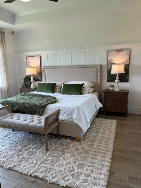 A cozy bedroom featuring a tufted bench, neutral tones, and elegant bedside lamps for a serene ambiance.