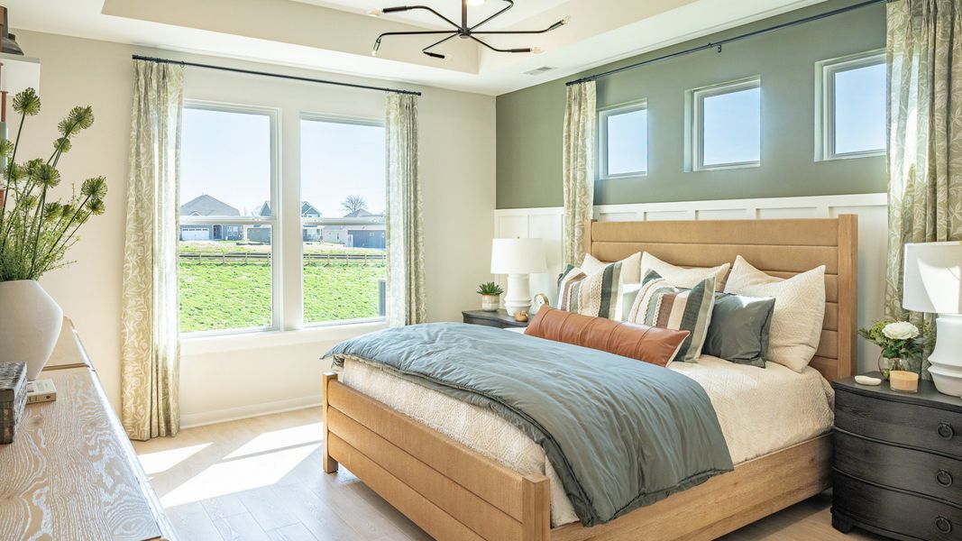 Primary suite with bright natural lighting form windows, hard surface flooring, and tray ceiling Primary suite with bright natural lighting form windows, hard surface flooring, and tray ceiling