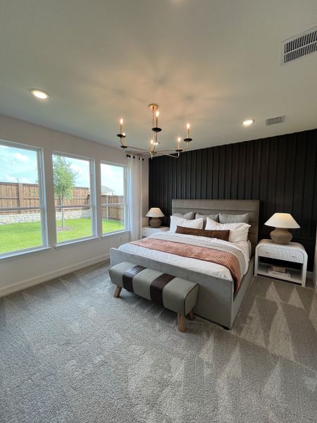 A cozy bedroom with a modern chandelier, plush carpet, and a serene view through large windows. A cozy bedroom with a modern chandelier, plush carpet, and a serene view through large windows.