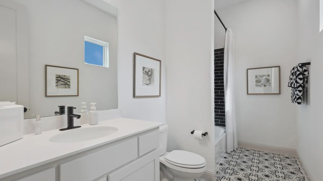 Elegant bathroom boasts handcrafted black fixtures, striking patterned tile, in Westside Preserve.