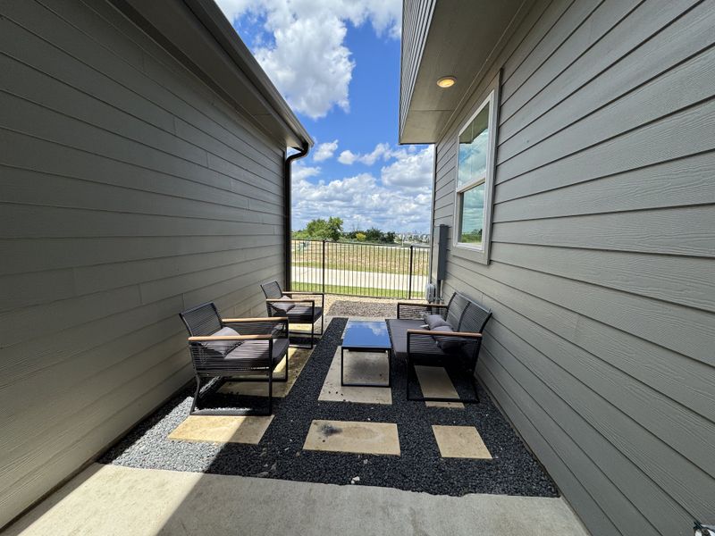 A cozy outdoor patio with modern seating, stone accents, and a view of the open sky and distant landscape.