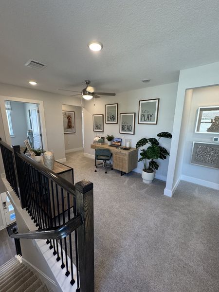 A cozy study nook with plush carpet, inspiring wall art, and natural light, perfect for creativity and focus.