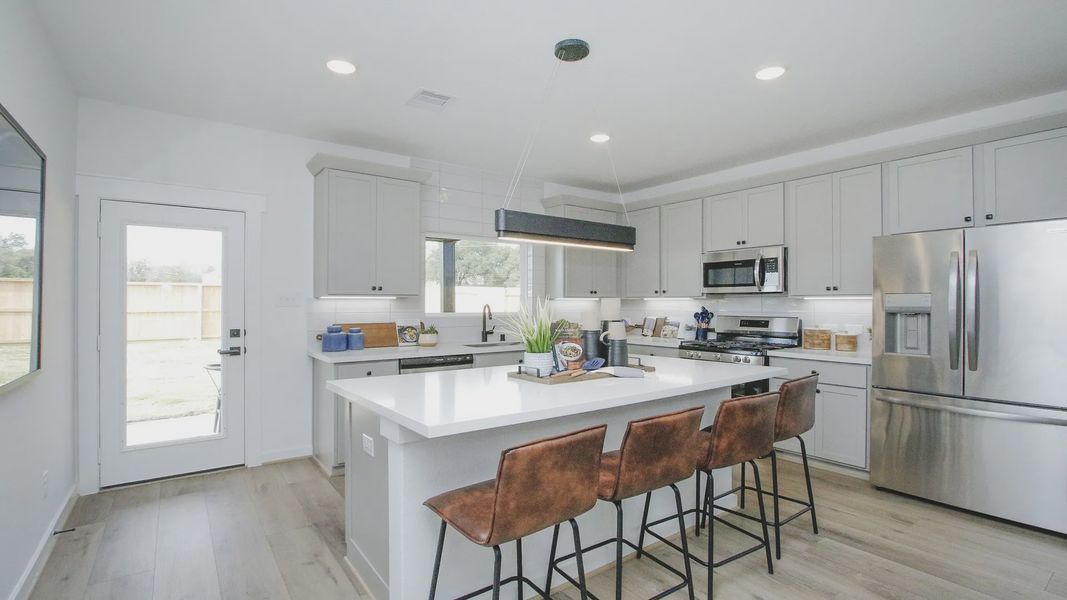 Elegant kitchen with stainless steel appliances, chic lighting, and sleek gray cabinets in Colony at Pinehurst.