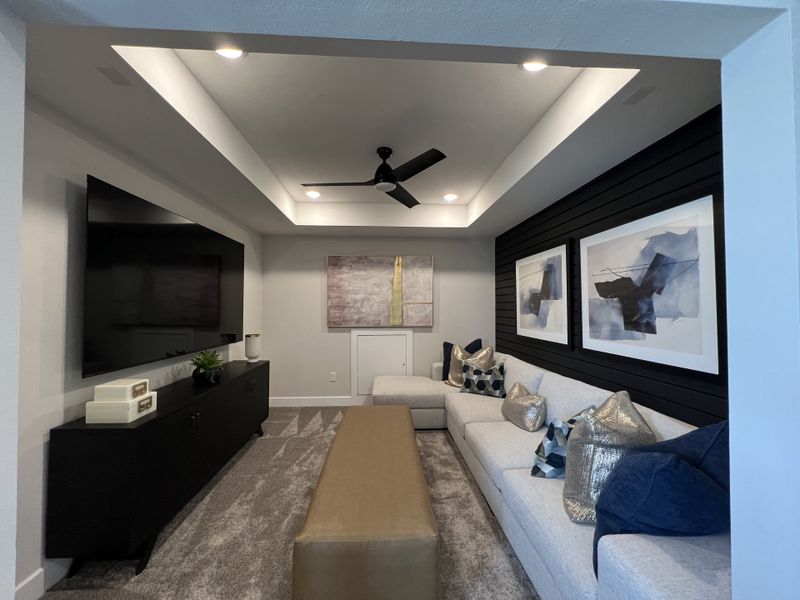 A cozy media room with a plush sectional, modern artwork, and ambient ceiling lighting for a sleek entertainment space.