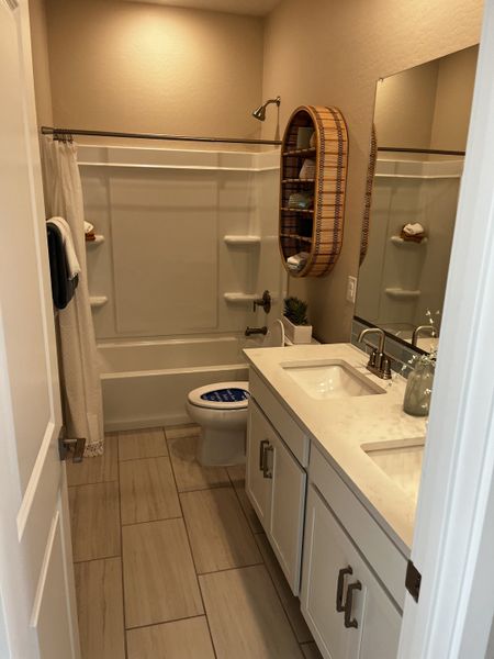 Modern bathroom with a double vanity, white cabinets, and a bathtub with built-in shelves. Warm lighting.