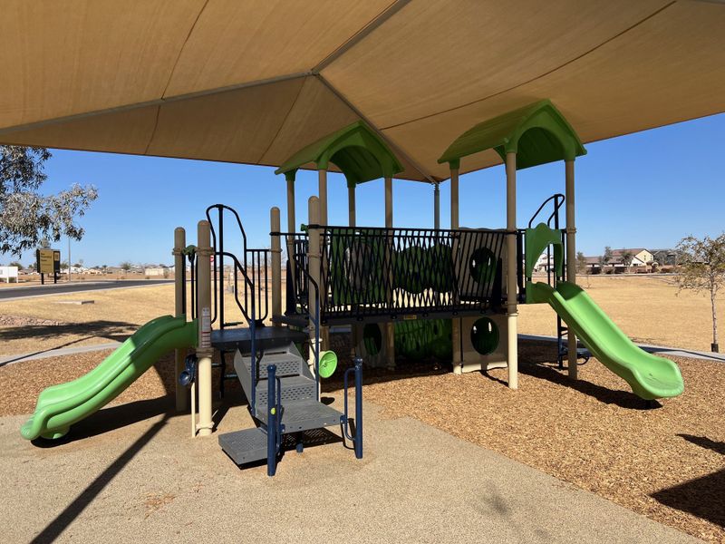 A vibrant playground with slides under a sunshade in Tortosa by KB Home, Maricopa, AZ.