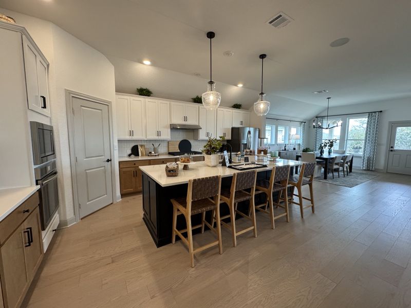 Spacious kitchen with a large island, pendant lights, and modern cabinetry, opening into a bright dining area.
