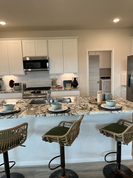 A modern kitchen with white cabinets, granite countertops, and elegant barstools, perfect for casual dining and entertaining.