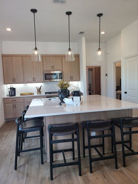 A stylish kitchen with a spacious island, pendant lights, and wooden cabinetry, creating an inviting and modern atmosphere.