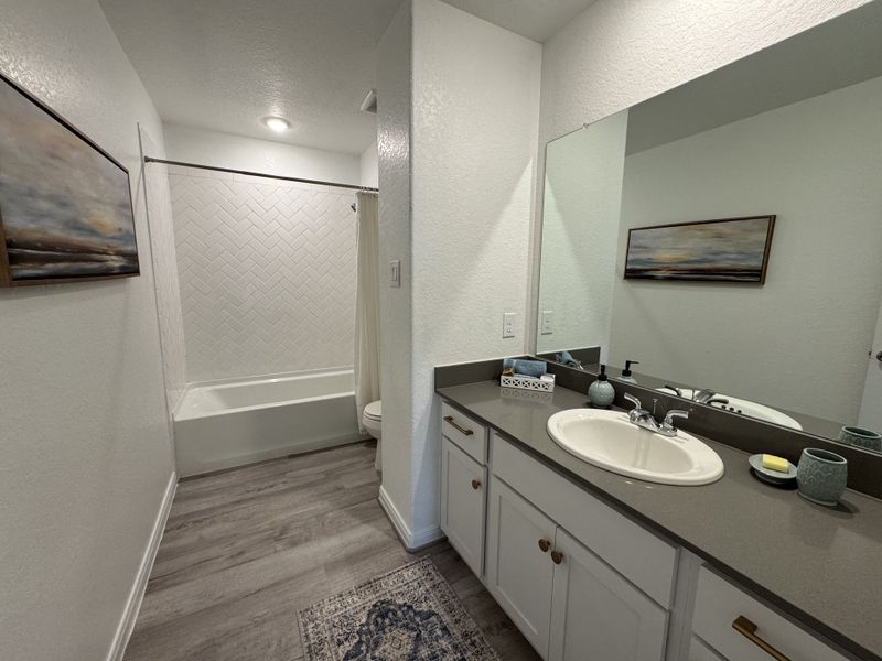 Modern bathroom with sleek gray countertop, white vanity, and herringbone-tiled shower for a stylish touch.