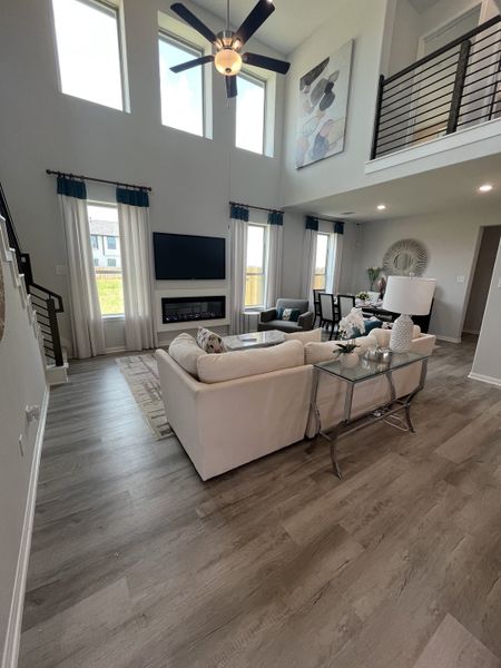 A spacious living area with a high ceiling, sleek fan, large windows, and modern decor for a contemporary feel. A spacious living area with a high ceiling, sleek fan, large windows, and modern decor for a contemporary feel.