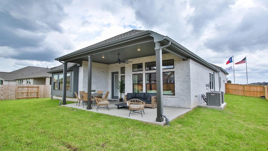 Spacious patio with ceiling fans and sleek brick exterior epitomizes luxury in Coastal Point, Texas.