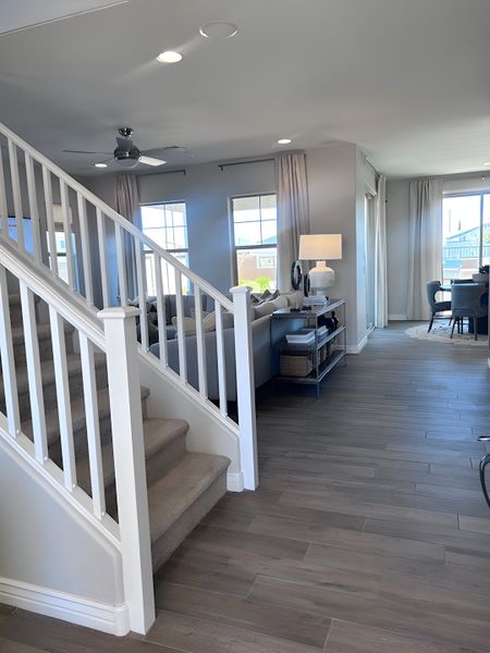 A modern living space featuring open layout, wood floors, elegant staircase, and ample natural light from large windows. A modern living space featuring open layout, wood floors, elegant staircase, and ample natural light from large windows.