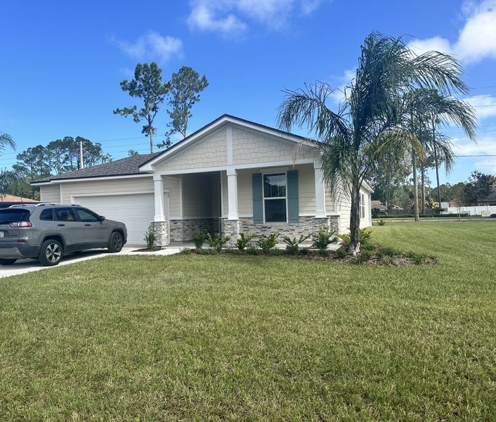 A charming single-story home with stone accents and manicured lawn in Palm Coast by Brightland Homes (Palm Coast, FL).