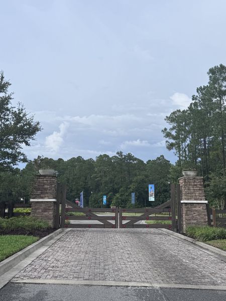 A gated entrance with stone pillars and surrounded by nature in Reverie at TrailMark by Dream Finders Homes (St. Augustine, FL).