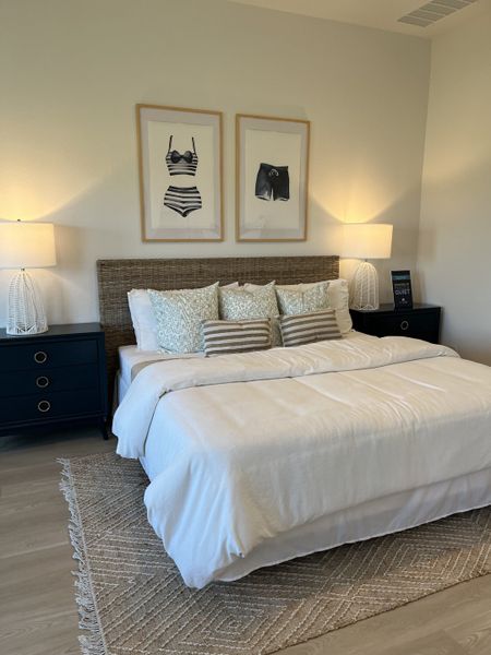 A cozy bedroom featuring a woven headboard, soft white bedding, and stylish artwork. Warm lighting on elegant side tables. A cozy bedroom featuring a woven headboard, soft white bedding, and stylish artwork. Warm lighting on elegant side tables.
