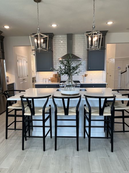 A modern kitchen with an island, elegant pendant lights, dark cabinetry, and stylish barstools. A modern kitchen with an island, elegant pendant lights, dark cabinetry, and stylish barstools.