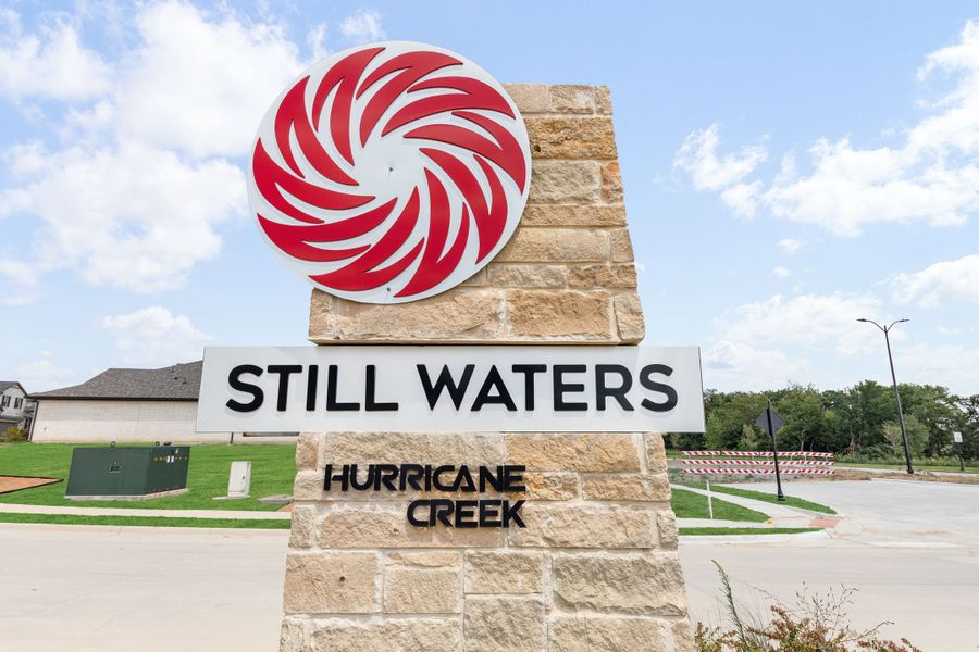 Still Waters at Hurricane Creek community entrance sign on a stone pillar with red swirl logo