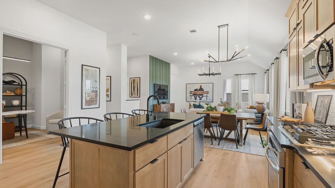 Sleek cabinetry, black island, and elegant chandelier enhance this Southern Pointe open-concept design.