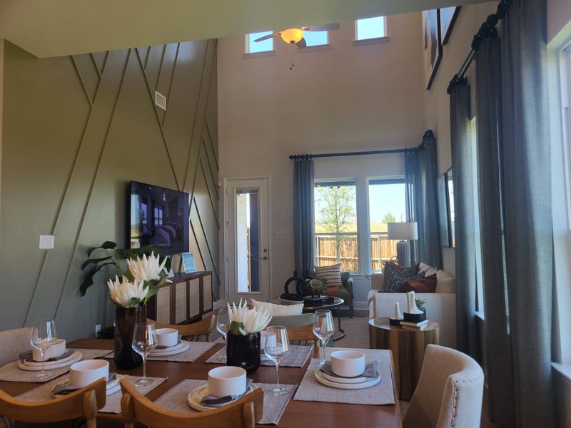A modern living area with high ceilings, geometric accent wall, and elegant dining setup.