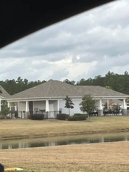 A serene view of a spacious lakeside clubhouse in Four Seasons at Lakes of Cane Bay by K. Hovnanian® Homes (Summerville, SC).