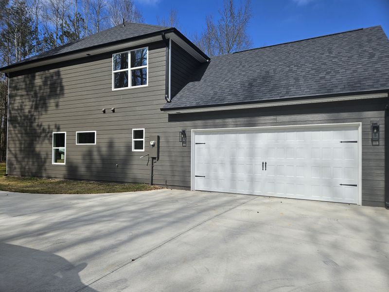 A dark gray house exterior with a white double garage door and multiple windows for natural lighting.