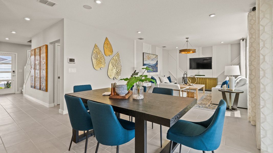 Open dining and living space in The Highbourne at Hamilton Bluff featuring bold seating, tile floors, and natural light.