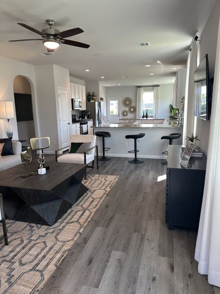 A contemporary living area with sleek furnishings, open kitchen layout, and stylish decor, featuring warm wood flooring.