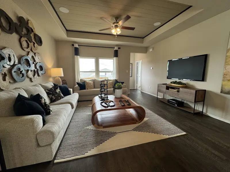 A cozy living room with plush sofas, a modern wooden coffee table, and a wall-mounted TV for a comfortable ambiance.