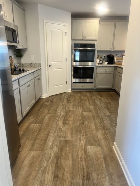 A modern kitchen with sleek stainless steel appliances, light cabinetry, and warm wood flooring.