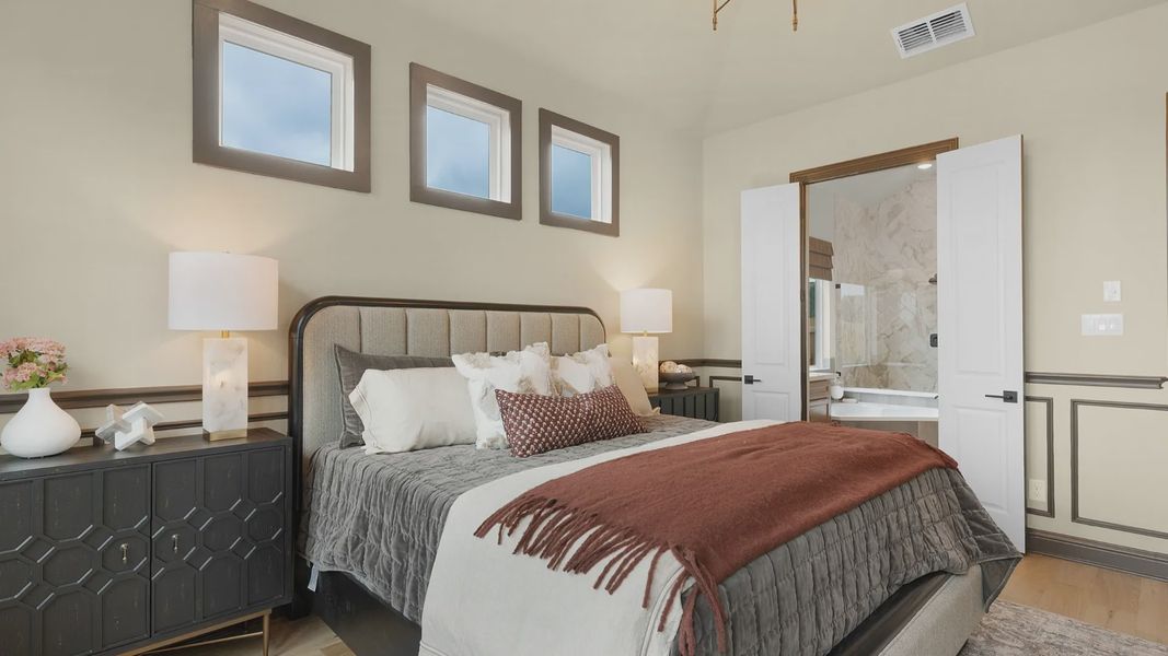 Owner’s suite with abundant natural light, woodwork details, and warm-toned flooring for a refined feel.