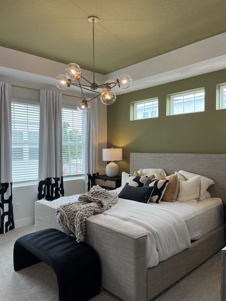 A chic bedroom with a plush bed, stylish pendant lighting, and modern decor accents.