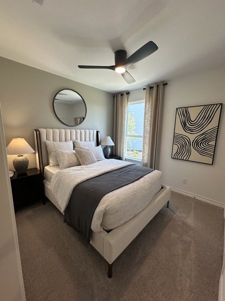 A cozy bedroom featuring a plush bed, modern ceiling fan, and stylish decor with neutral tones.