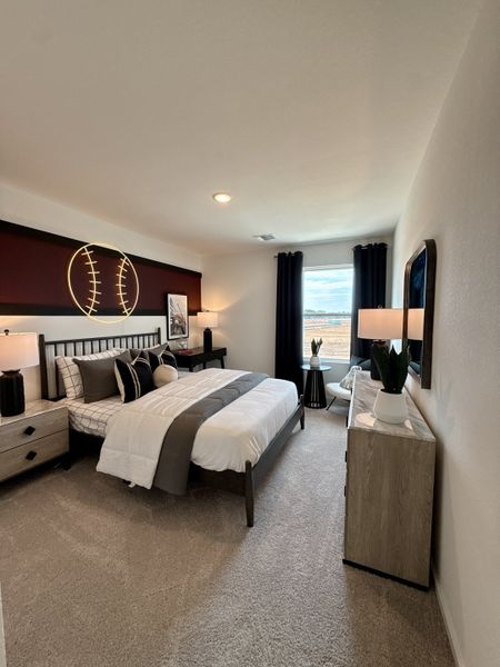 A cozy bedroom with a baseball theme, featuring modern furnishings, plush carpet, and ample natural light. A cozy bedroom with a baseball theme, featuring modern furnishings, plush carpet, and ample natural light.