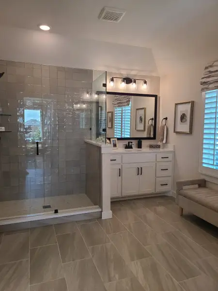 A sleek bathroom featuring a tiled shower, white vanity, and elegant lighting with cozy seating for a relaxed ambiance. A sleek bathroom featuring a tiled shower, white vanity, and elegant lighting with cozy seating for a relaxed ambiance.