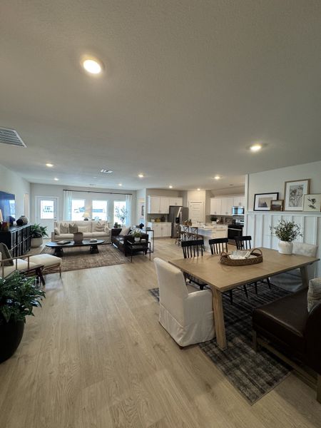 An inviting open-concept living space with sleek light wood flooring, cozy seating, and a modern dining area.