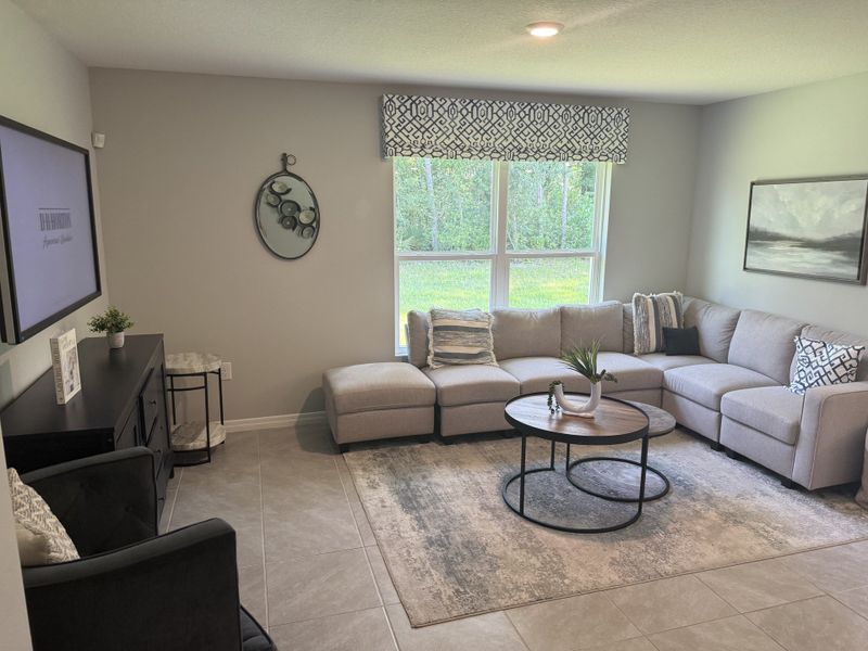 A cozy living room featuring a gray sectional, modern rug, round coffee table, and large window for natural light.