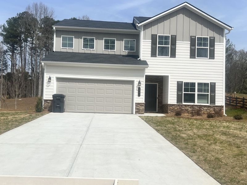 A charming two-story home in Swetlake Grove by Kerley Family Homes(Mableton, GA), features a white and gray exterior with dark shutters, a two-car garage, and a freshly poured concrete driveway. A charming two-story home in Swetlake Grove by Kerley Family Homes(Mableton, GA), features a white and gray exterior with dark shutters, a two-car garage, and a freshly poured concrete driveway.