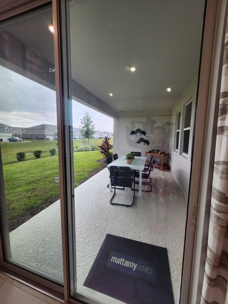 A covered patio with a sleek dining set and lush green views, offering a relaxing outdoor space.