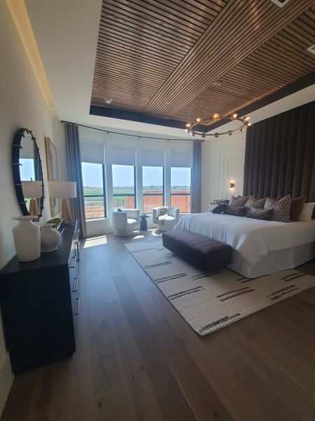 A luxurious bedroom with a wood accent ceiling, large windows, and modern decor, creating a serene atmosphere.