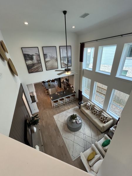 A spacious open-concept living area with a high ceiling, large windows, modern decor, and stylish furnishings.