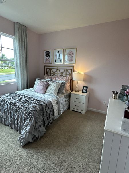 A cozy bedroom with a pastel pink accent wall, ruffled bedding, and soft lighting, creating a serene ambiance.