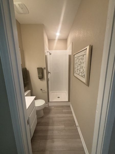 A cozy bathroom featuring a sleek shower with a modern glass door, light wood flooring, and soft beige walls. A cozy bathroom featuring a sleek shower with a modern glass door, light wood flooring, and soft beige walls.