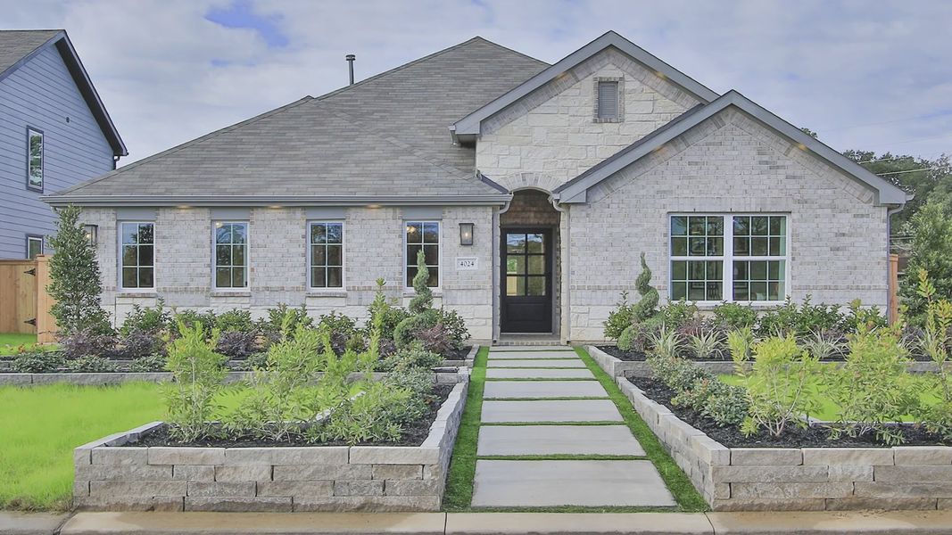 Luxurious stone facade with pristine landscaping in Colony at Pinehurst, Texas.